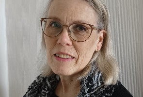 Nainen kuvattuna seinän edustalla.